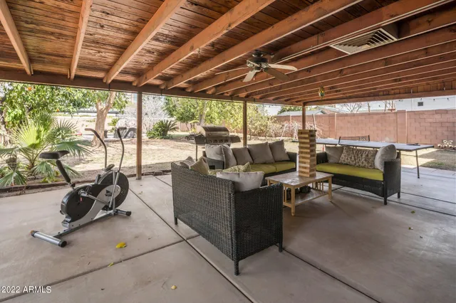 a view of a patio with table and chairs under an roof with a barbeque grill and couches