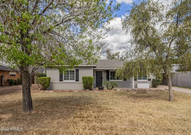 a front view of a house with a yard and potted plants
