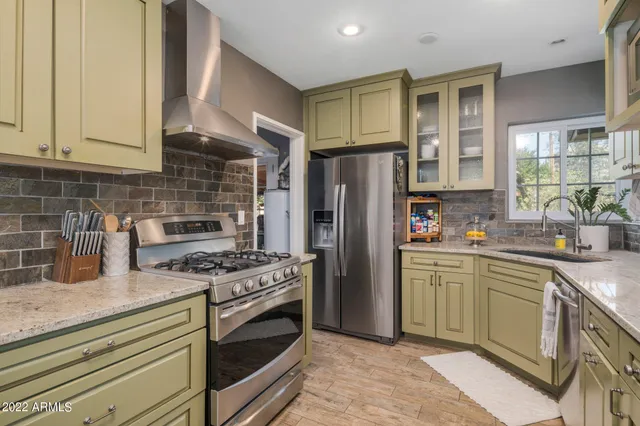 a kitchen with stainless steel appliances granite countertop a stove a refrigerator and a sink