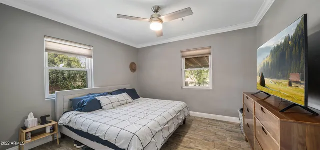 a bedroom with a bed television on desk and a window