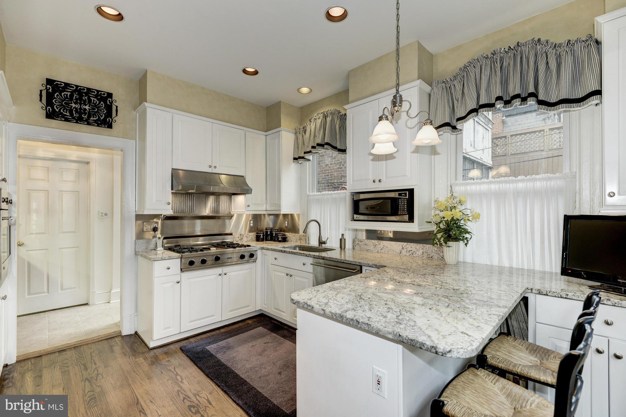 1616 S Street Northwest Washington, DC 20009 - Photo 12 of 30 a kitchen with stainless steel appliances kitchen island granite countertop a stove top oven a sink a counter space and cabinets