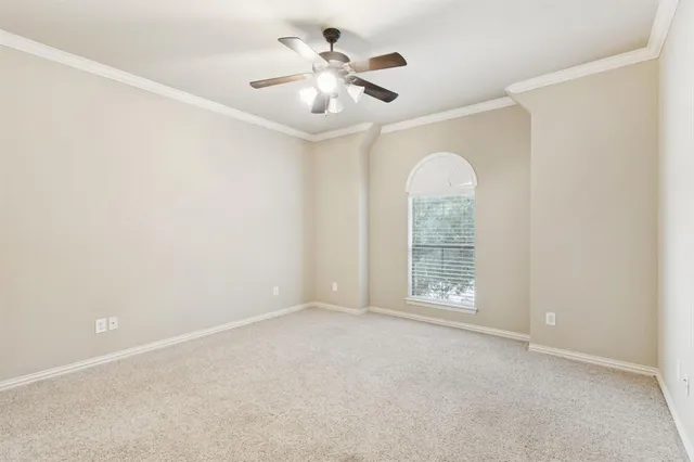 an empty room with chandelier fan and windows