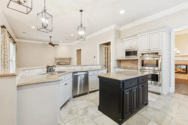 a kitchen with stainless steel appliances kitchen island granite countertop a sink a stove and cabinets