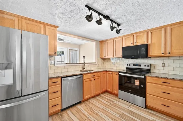 a kitchen with stainless steel appliances granite countertop a stove microwave and refrigerator
