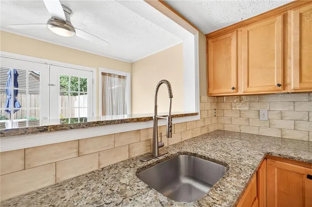 a kitchen with granite countertop a sink a window and cabinets