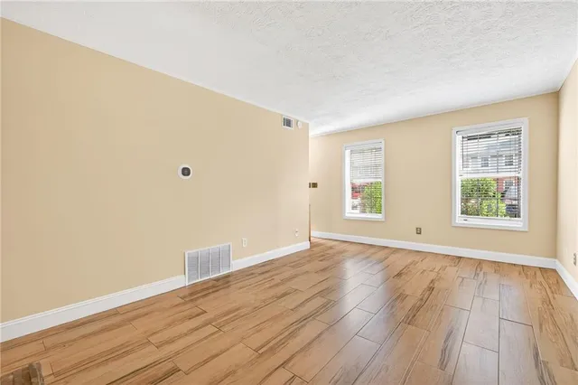 an empty room with wooden floor and windows