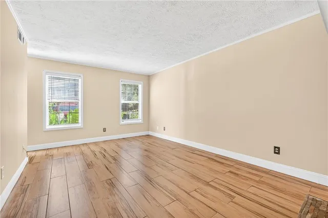 an empty room with wooden floor and windows