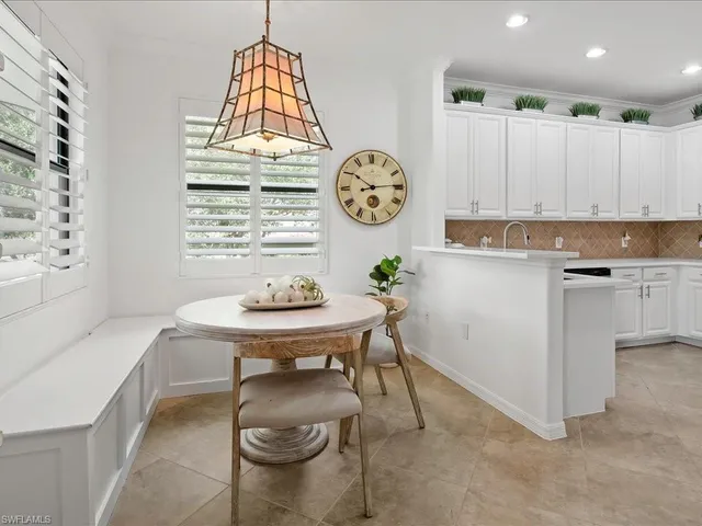 a room with a table chairs a clock and a window