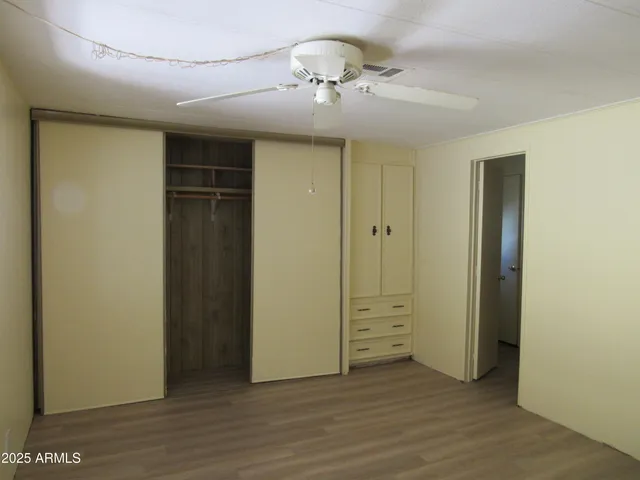 an empty room with wooden floor closet and windows