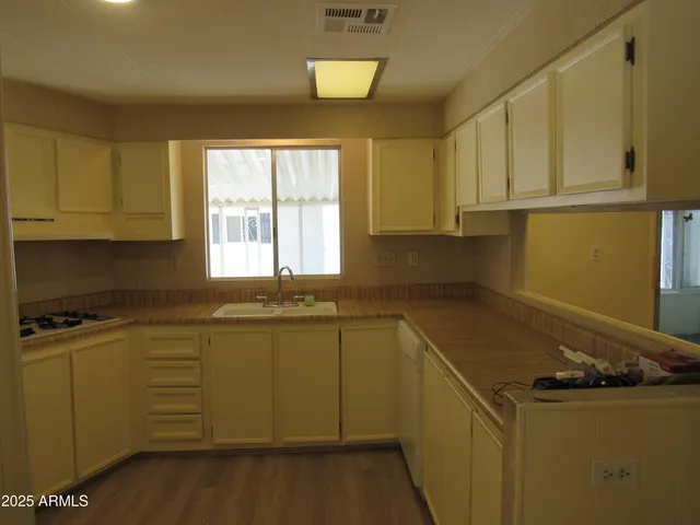 a kitchen with a sink a stove cabinets and wooden floor