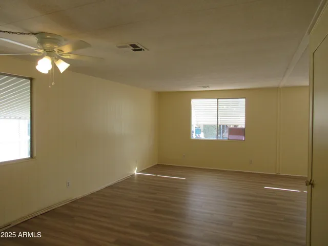 an empty room with wooden floor and windows
