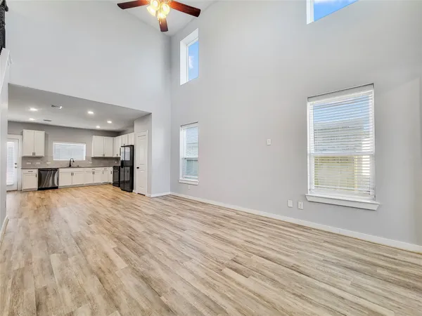 a large kitchen with stainless steel appliances granite countertop a stove a sink dishwasher a refrigerator and white cabinets with wooden floor