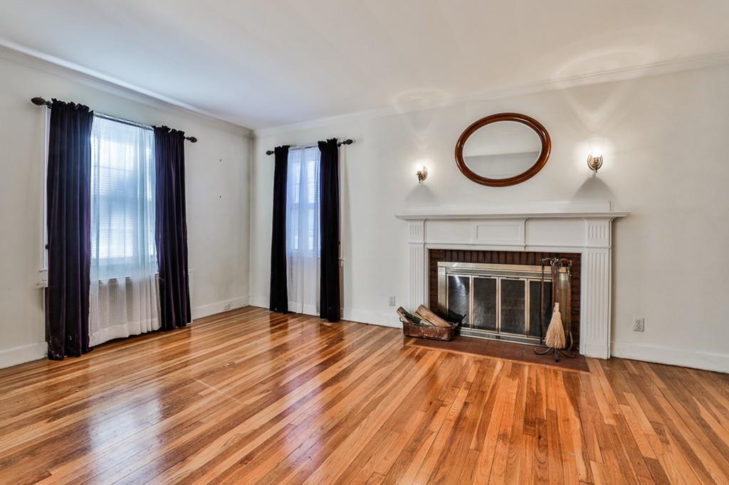 554 Brook Road Milton, MA 02186 - Photo 5 of 22 a view of an empty room with wooden floor a fireplace and a window
