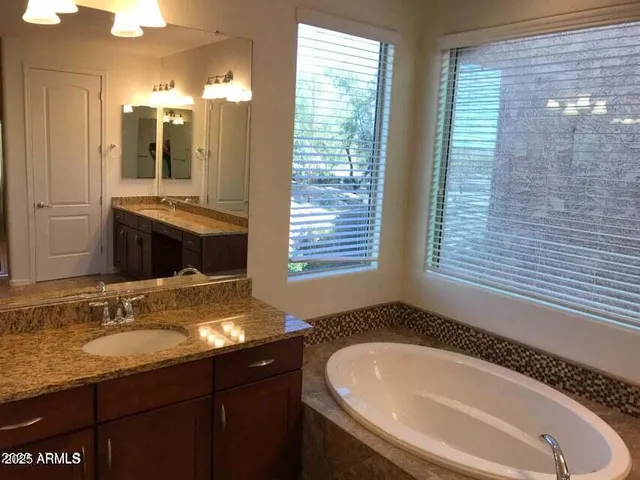 a bathroom with a granite countertop sink and a bathtub