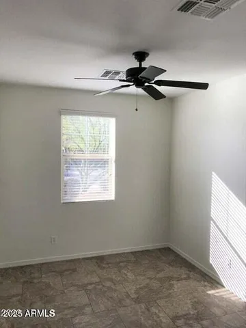 an empty room with windows and fan