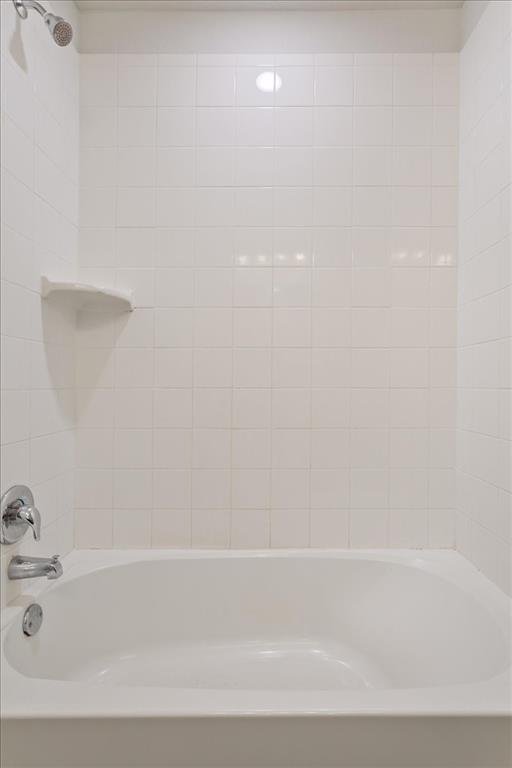 6317 Elephant Butte Drive Waco, TX 76708 - Photo 31 of 39 White tiled shower-over-tub with a chrome showerhead, single-handle faucet, and integrated soap dish