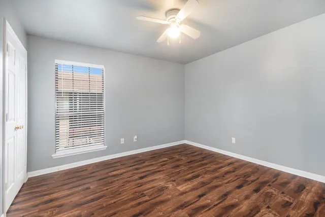 an empty room with wooden floor and windows