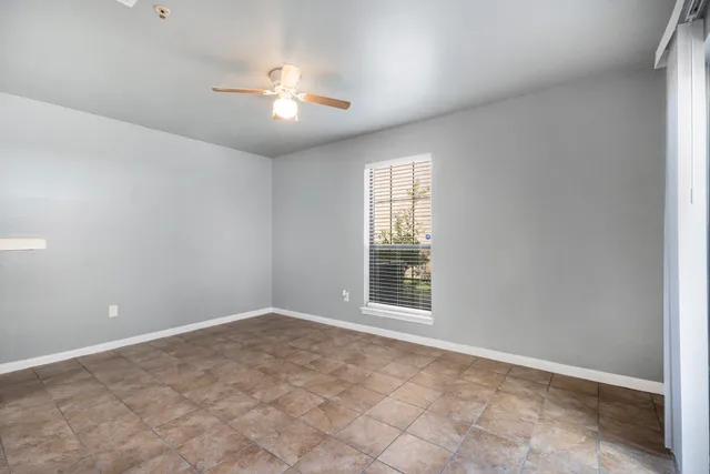 an empty room with windows and chandelier fan
