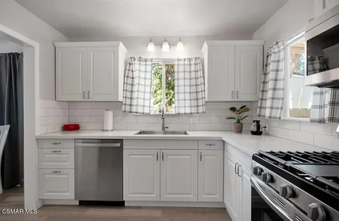 a kitchen with cabinets appliances a sink and a window
