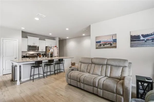 a living room with stainless steel appliances kitchen island granite countertop furniture and a wooden floor