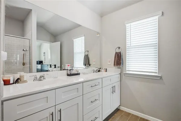 a bathroom with double sink large mirror next to a window