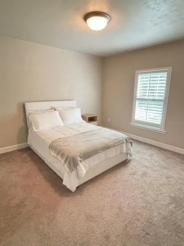 a bed sitting in a spacious bedroom next to a window