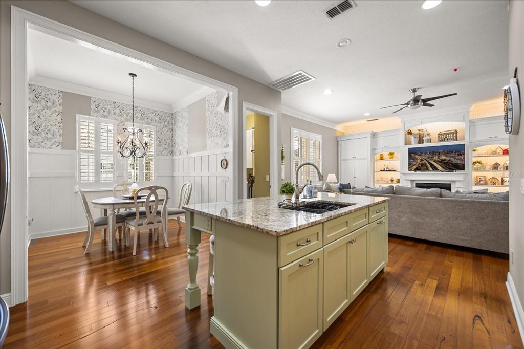 815 Spring Park Loop Celebration, FL 34747 - Photo 16 of 51 a kitchen with stainless steel appliances granite countertop a stove top oven a sink dishwasher a dining table and chairs with wooden floor