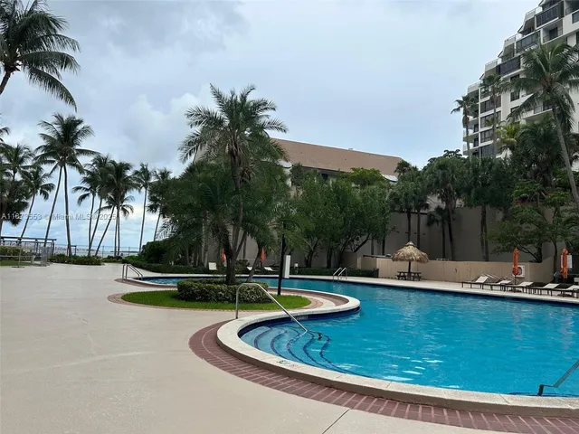 a view of a swimming pool with a yard and palm trees