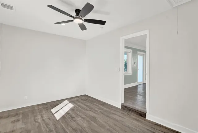 an empty room with wooden floor and a ceiling fan