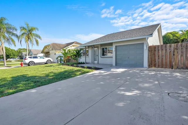 a view of a house with a yard and palm trees
