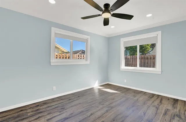 an empty room with wooden floor and windows