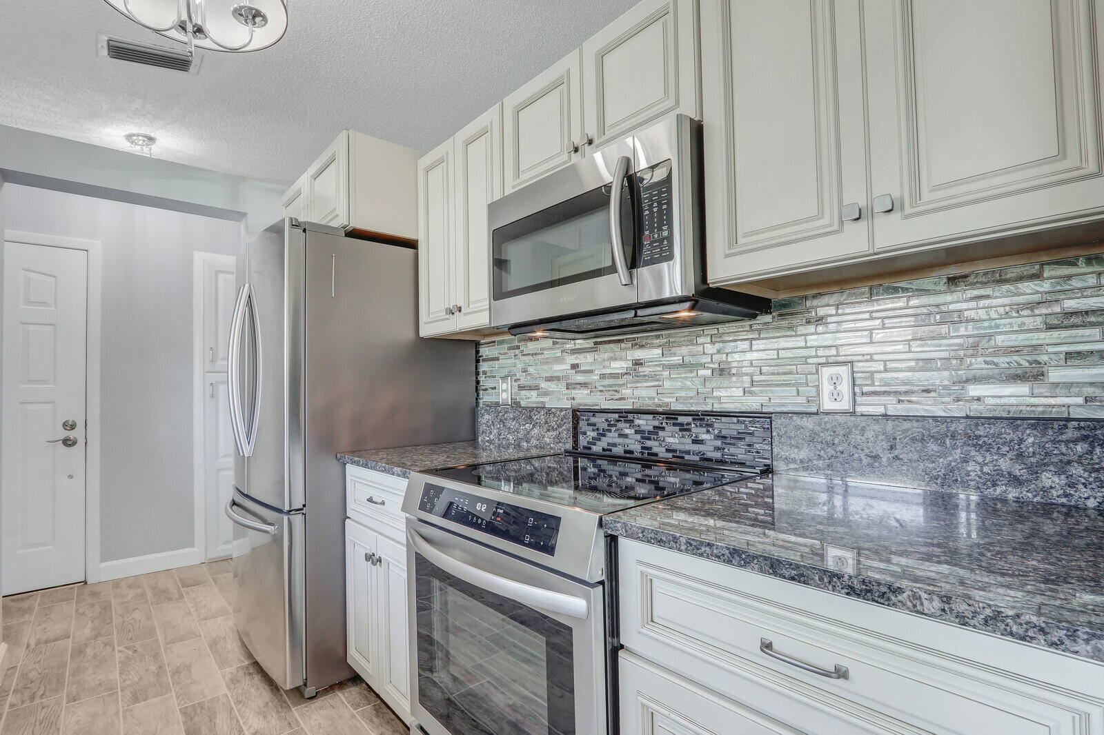 1102 Wingfoot Drive, Unit D Jupiter, FL 33458 - Photo 11 of 30 a kitchen with stainless steel appliances granite countertop white cabinets and a stove top oven