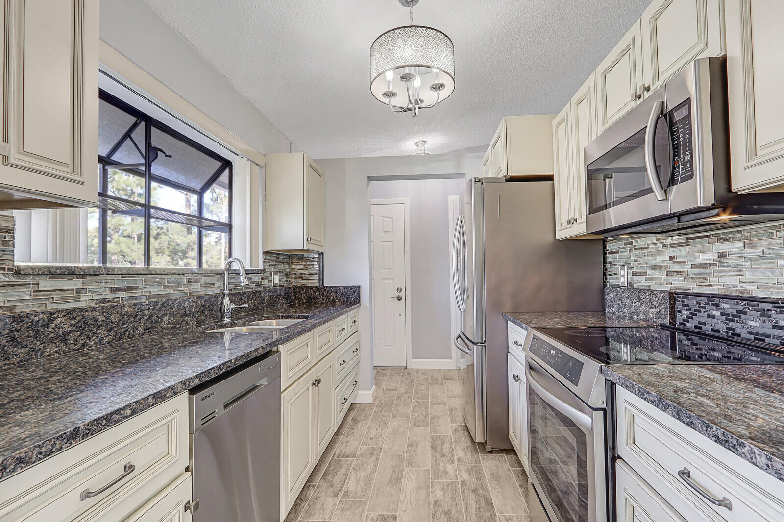 1102 Wingfoot Drive, Unit D Jupiter, FL 33458 - Photo 13 of 30 a kitchen with stainless steel appliances granite countertop a sink stove and cabinets