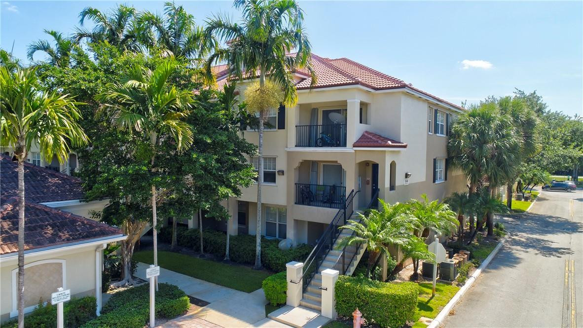 5840 West Sample Road, Unit 308 Coral Springs, FL 33067 - Photo 54 of 54 a view of a white house with a big yard and potted plants