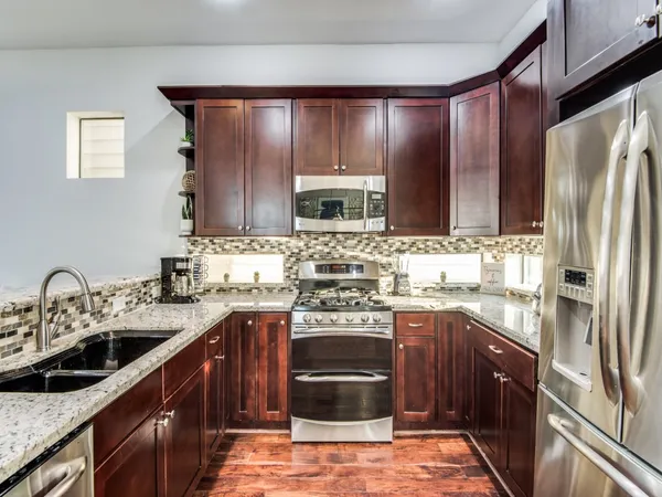 a kitchen with stainless steel appliances granite countertop a sink stove microwave and refrigerator