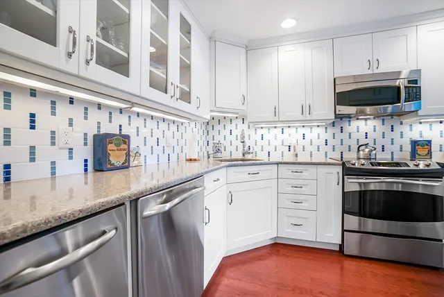 a kitchen with stainless steel appliances granite countertop a sink a stove and a microwave oven with cabinets