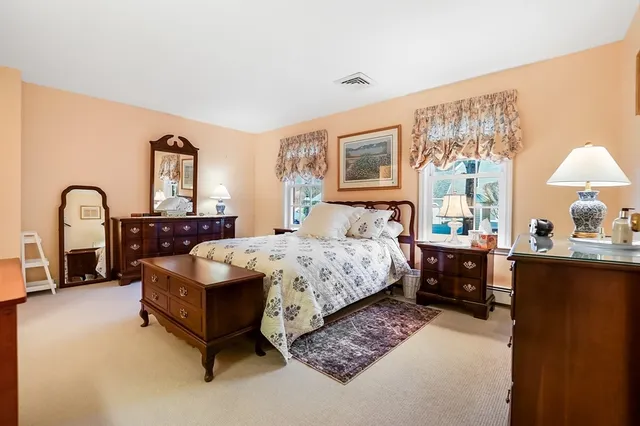 a bedroom with a bed large window and a dresser