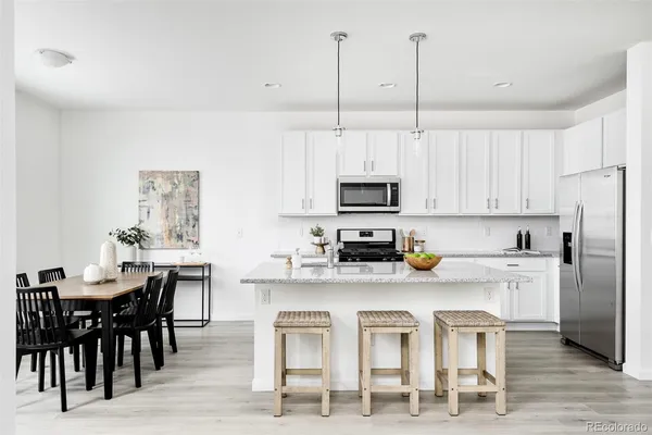 a kitchen with white cabinets and chairs