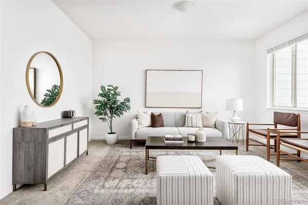 a living room with furniture and a large mirror next to a window