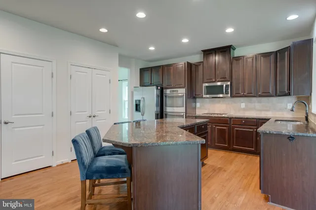 a kitchen with kitchen island granite countertop wooden cabinets and a refrigerator