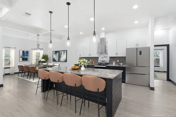 a kitchen with stainless steel appliances granite countertop a refrigerator a sink a stove a dining table chairs and white kitchen view