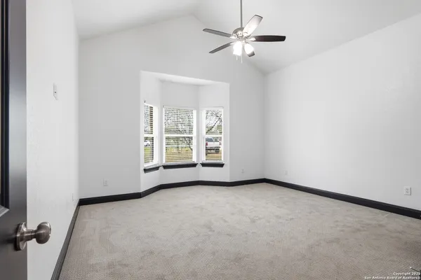 an empty room with windows and fan
