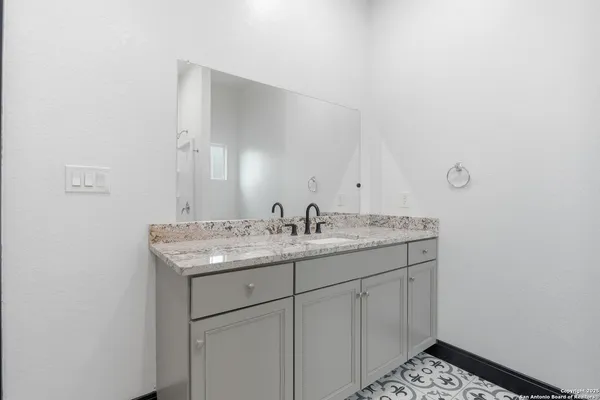 a bathroom with a granite countertop sink and a mirror