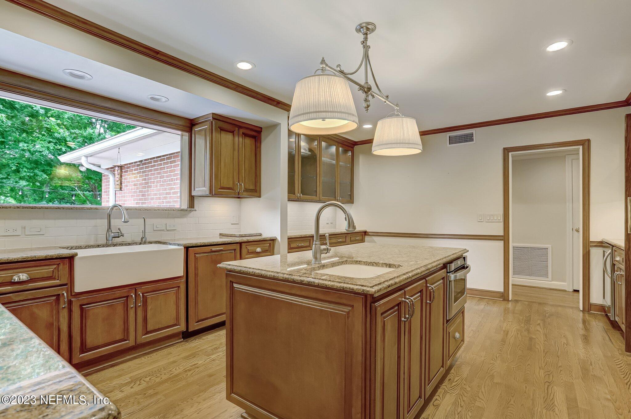 4143 Sherwood Road Jacksonville, FL 32210 - Photo 24 of 67 a kitchen with a sink dishwasher a stove a dining table and chairs with wooden floor