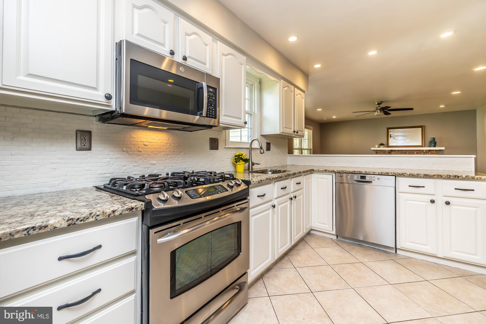 374 Devon Drive Exton, PA 19341 - Photo 26 of 50 a kitchen with granite countertop a stove top oven a sink dishwasher and white cabinets with wooden floor