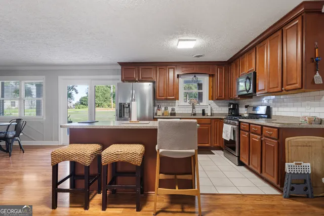 a kitchen with stainless steel appliances granite countertop a stove top oven a sink dishwasher and a refrigerator with wooden cabinets