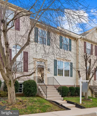 a view of a white house next to a yard with large trees
