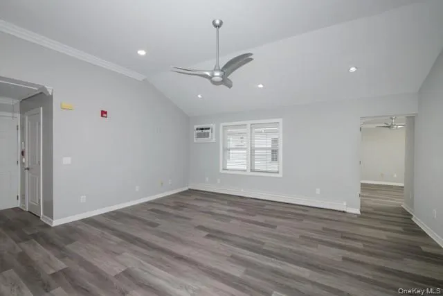 an empty room with wooden floor ceiling fan and windows
