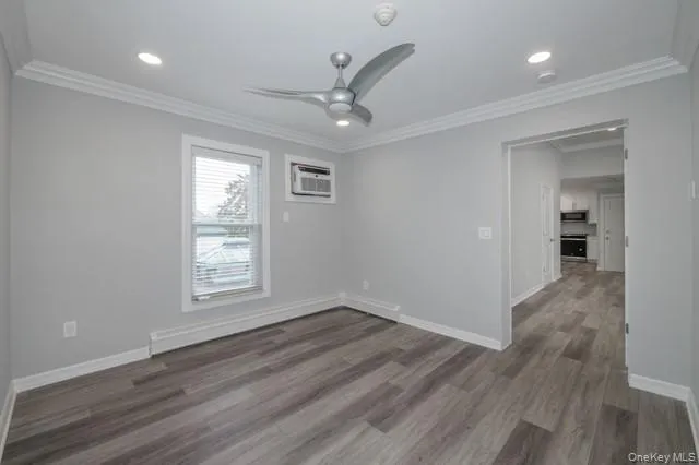 an empty room with wooden floor a ceiling fan and windows