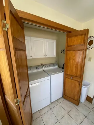 a view of a small white house next to a yard and large trees